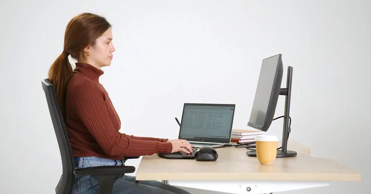 Person at an ergonomic desk setup with correct seated posture